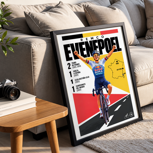 A framed cycling poster leaning against a beige sofa in a living room setting. The poster features a stylized illustration of cyclist Remco Evenpoel on a road bike, with bold text reading 'REMCO EVENPOEL' and red, yellow, and black graphic blocks.