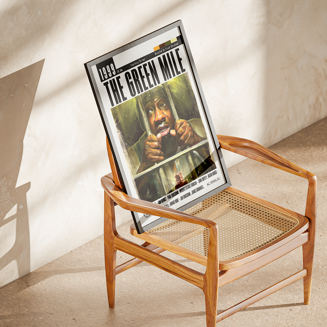 A framed 'The Green Mile' movie poster leaning against a mid-century modern wooden armchair in a sunlit room with textured plaster walls.