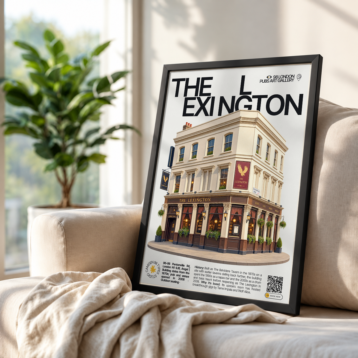 A framed poster leaning against a beige sofa in a bright living room. The poster features the text 'THE L EXINGTON' above an illustrated corner building with storefront details and small decorative text at the bottom.