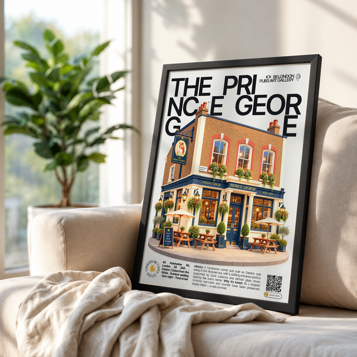A framed art print leaning against a beige sofa in a bright, modern room. The print features a black-and-white illustrated design with the text 'THE PRINCE GEORGE' and a colorful illustration of a pub exterior.