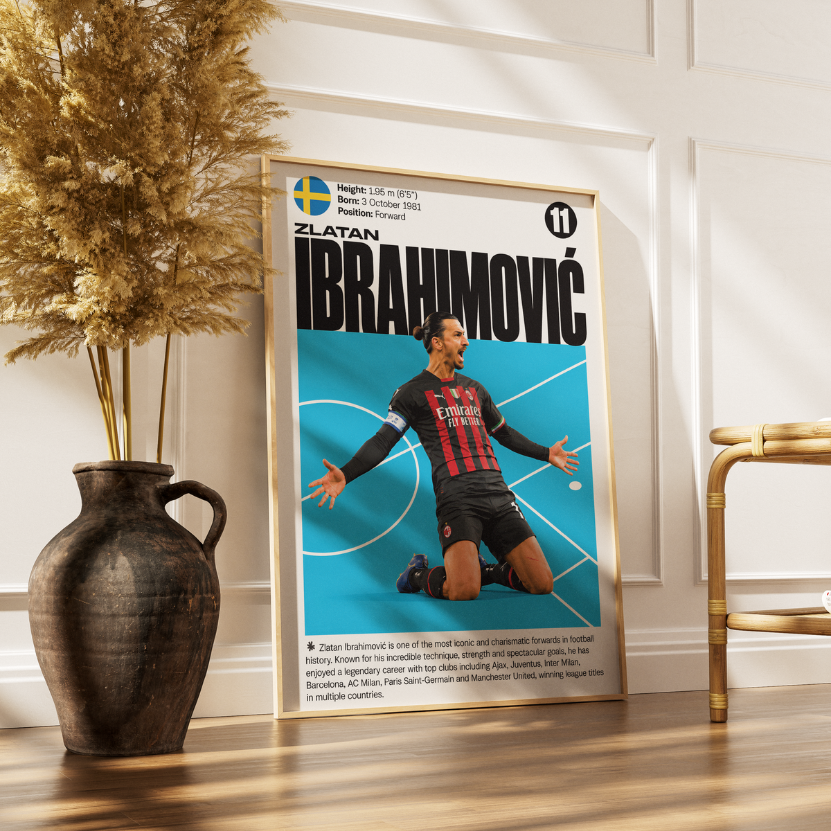 A framed vertical poster featuring Zlatan Ibrahimovic with a blue background and his AC Milan jersey, styled on a wooden floor next to a dark ceramic vase with dried grass and a gold side table.