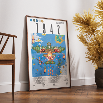 A framed vintage-style poster leaning against a white wall on a wooden floor, next to a chair and a potted plant. The poster features the title “1942” and a colorful illustration from Ghibli’s Spirited Living with a CAPCOM logo at the top right.