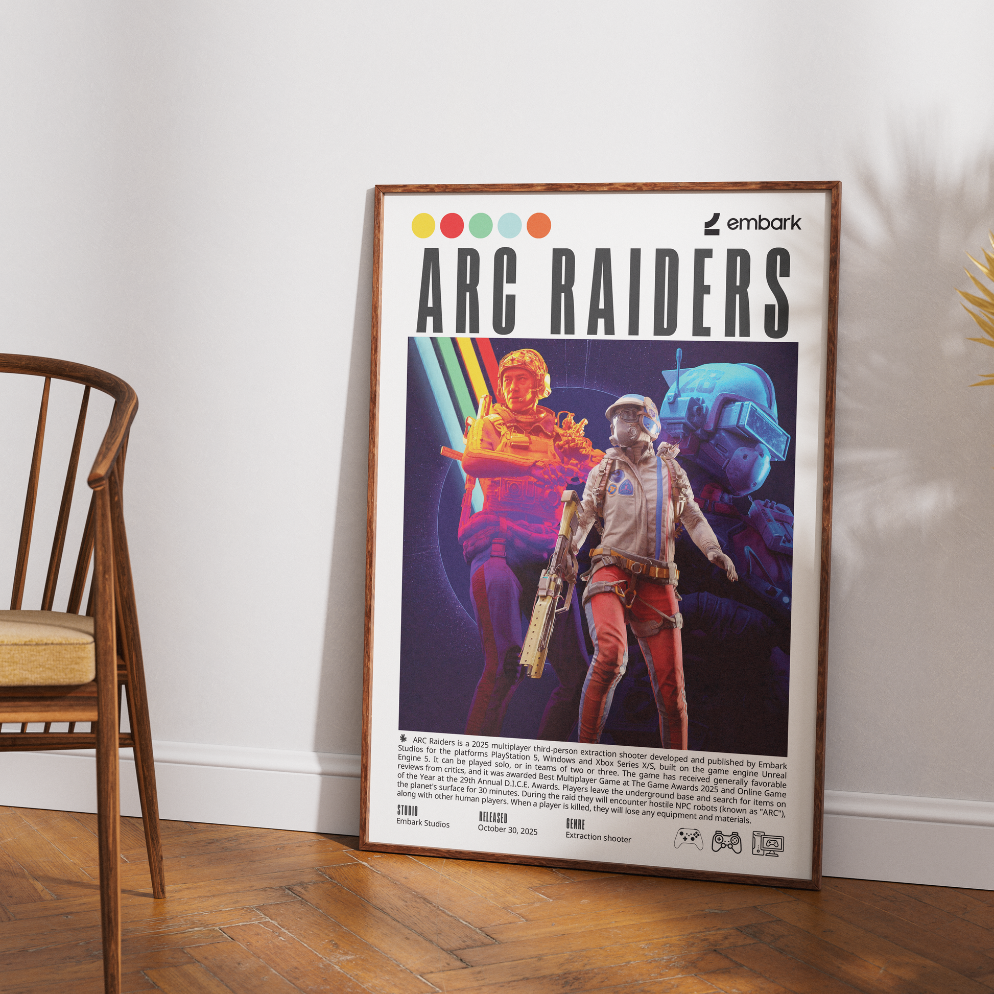 A framed poster titled 'ARC RAIDERS' with colorful sci-fi character artwork and the 'embark' logo, leaning against a white wall on a wood floor next to a wooden chair.