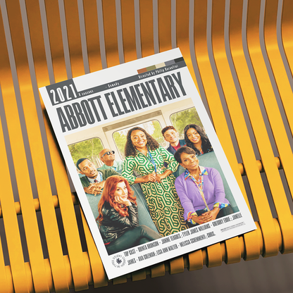 A printed magazine or booklet titled '2021 Abbott Elementary' lies on a yellow slatted bench. The cover shows a group photo of children and includes a list of names at the bottom.