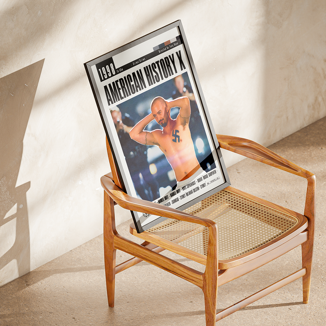 A framed print of the 1990 American History X movie poster leaning against a wooden cane-seated chair in a sunlit room.