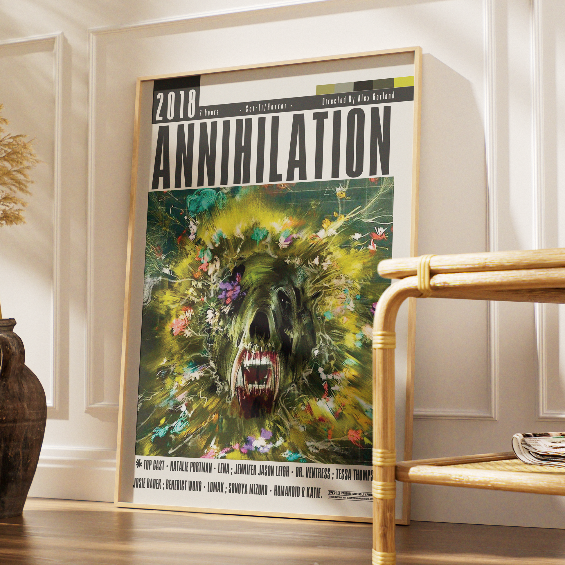 A framed music poster for the band 'Annihilation' leaning against a white paneled wall in a styled interior setting with a wooden shelf and basket visible.