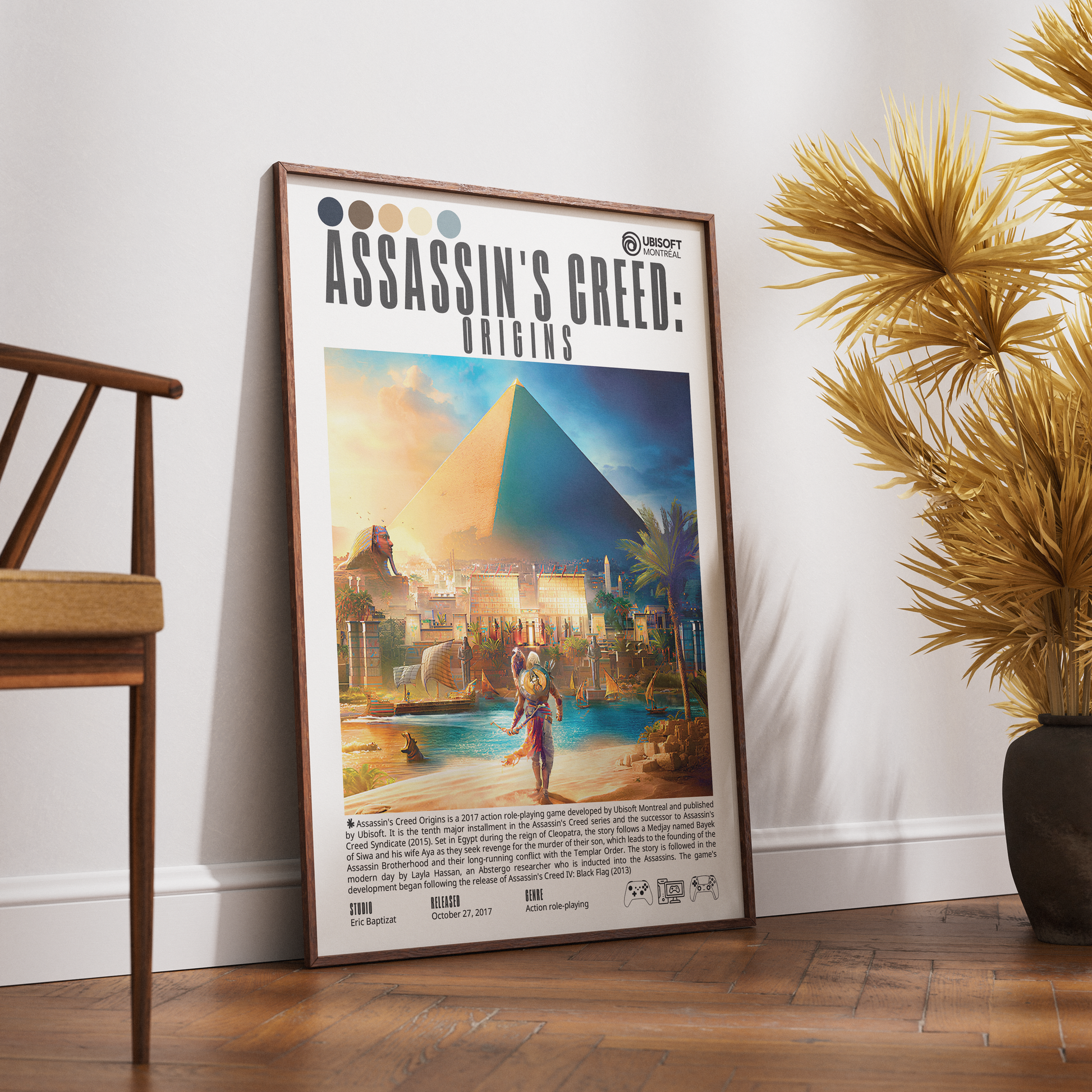 A framed Assassin's Creed: Origins poster leaning against a white wall on a wooden floor, styled in a room with a wooden chair on the left and a potted palm on the right.