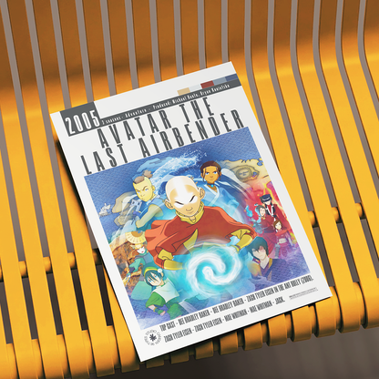A printed poster or art print for the 2005 film Avatar: The Last Airbender, featuring illustrated characters and title text, photographed resting on a yellow slatted bench.