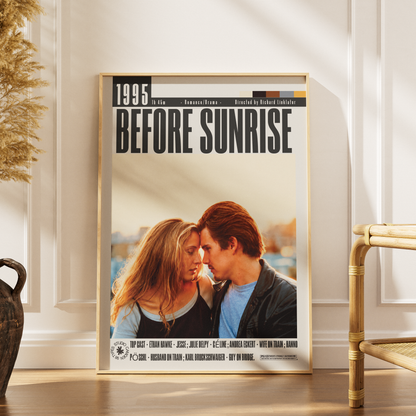 A framed movie poster for 'Before Sunrise' leaning against a white paneled wall on a wooden floor, with a dried plant and a bamboo chair partially visible in the room.