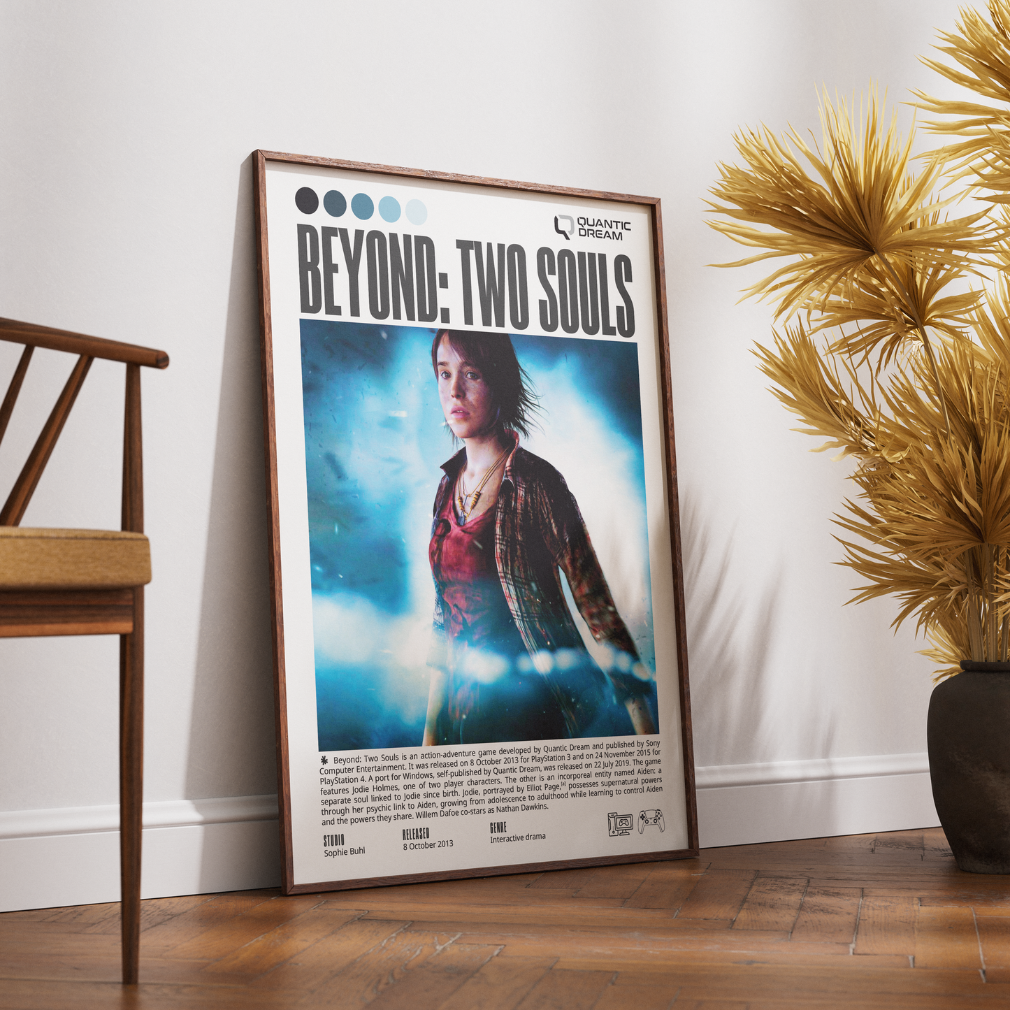 A framed 'Beyond: Two Souls' movie poster leaning against a white wall on a wooden floor, with a wooden chair on the left and a potted palm on the right.