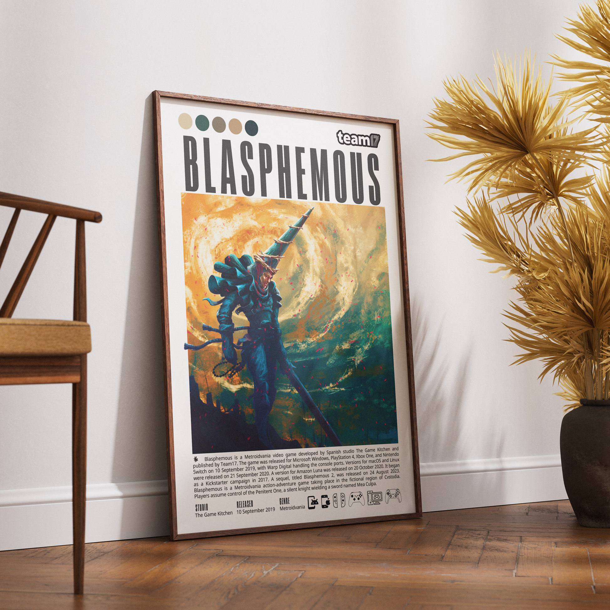 A framed art print titled 'BLASPHEOUS' leaning against a white wall on a wooden floor, styled in a room with a wooden chair on the left and a potted plant on the right.