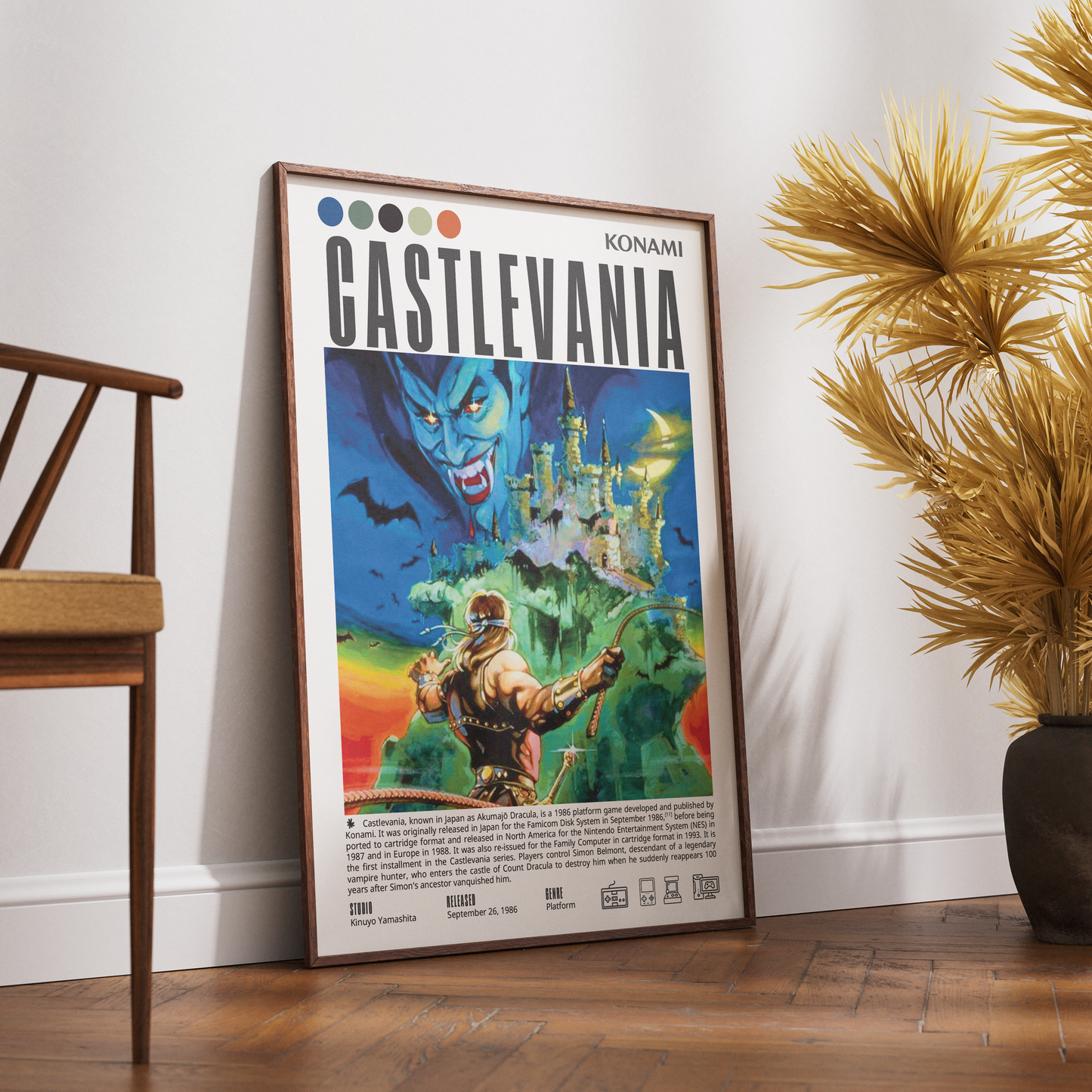 A framed Castlevania poster leaning against a white wall on a wooden floor, styled in a room with a wooden chair on the left and a potted palm on the right.