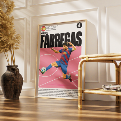 A framed vertical poster of soccer legend Lionel Messi in his FC Barcelona blue and red striped jersey, displayed on a wooden floor in a styled room next to a bamboo side table and a dark vase with dried grass.