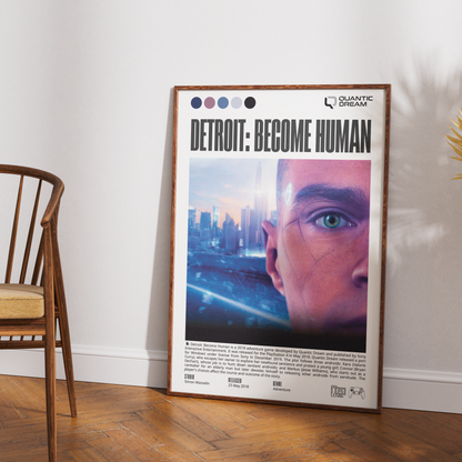 A framed poster leaning against a white wall on a wood floor, next to a wooden chair. The poster features the title 'DETROIT: BECOME HUMAN' and the brand 'QUANTIC DREAM' at the top, with a close-up of a human eye and city skyline artwork.