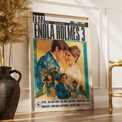 A framed movie poster for 'Enola Holmes 3' leaning against a white wall on a wooden floor, next to a dark ceramic vase with dried grass and part of a gold chair.
