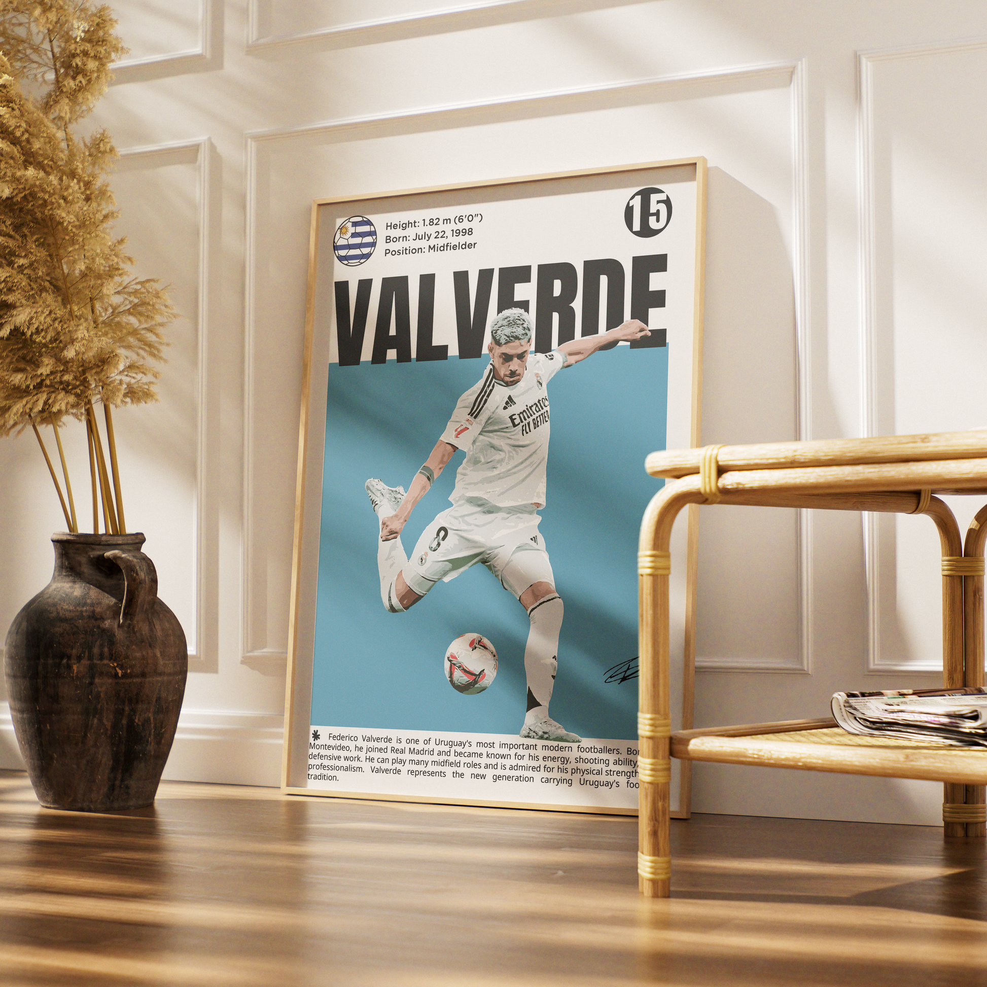 A framed soccer poster of Real Madrid player Javier Valverde, styled in a warm, modern interior setting with a wooden floor, a dark ceramic vase with dried grass, and a bamboo side table.