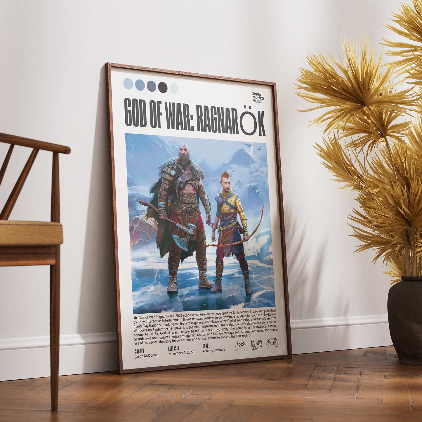 A framed 'God of War: Ragnarök' poster leaning against a white wall on a wooden floor, styled in a room with a wooden chair on the left and a potted plant on the right.