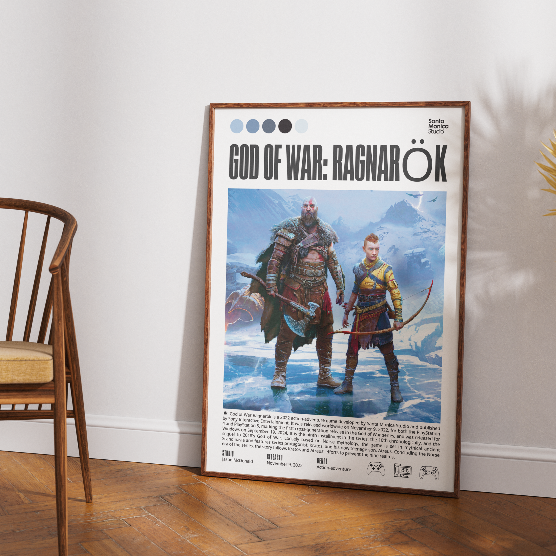 A framed poster of the video game God of War: Ragnarök leaning against a white wall on a wooden floor, next to a wooden chair.