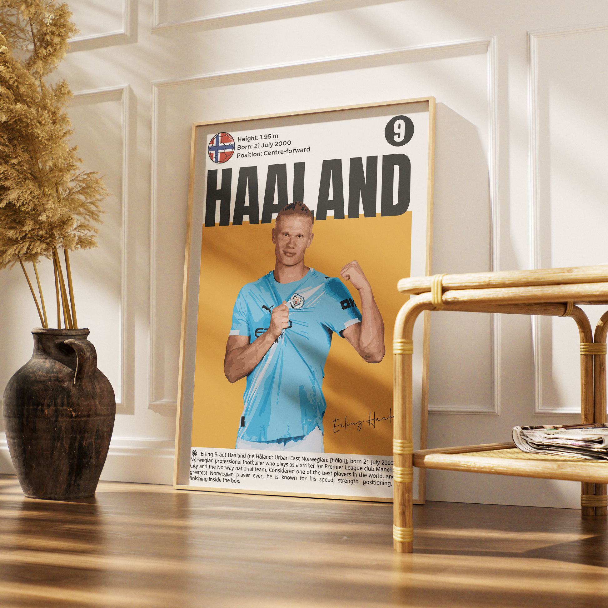 A framed poster of footballer Edinson Cavani 'Haaland' leaning against a white paneled wall on a wooden floor, next to a bamboo side table and a dark ceramic vase with dried grass.