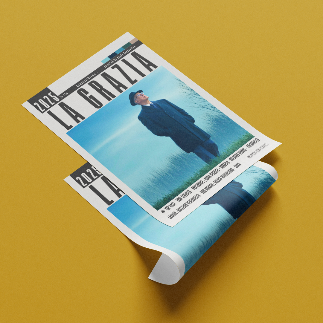 A rolled magazine or poster titled "LA GRAZIA" with a cover photo of a man in a dark suit against a blue sky, displayed on a solid mustard yellow background.