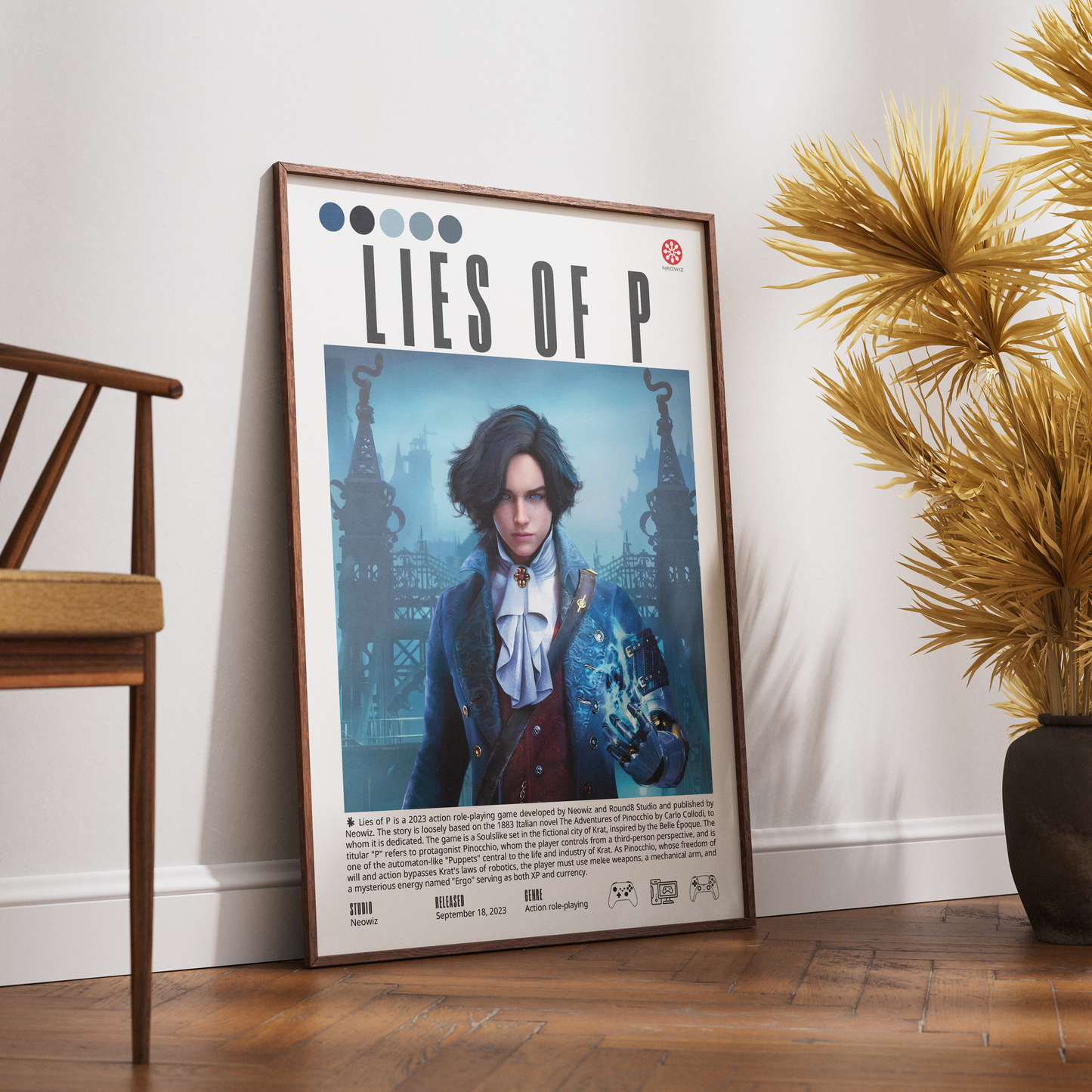 A framed poster leaning against a white wall on a wooden floor, next to a wooden chair and a potted palm. The poster features the title 'LIES OF P' and an illustration of a young man in a blue coat holding a glowing orb.