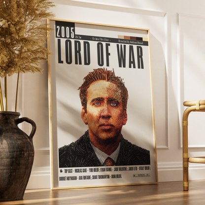 A framed movie poster for 'Lord of War' (2005) leaning against a white wall on a wooden floor, styled in a home interior next to a dark ceramic vase with dried grass and a bamboo chair.