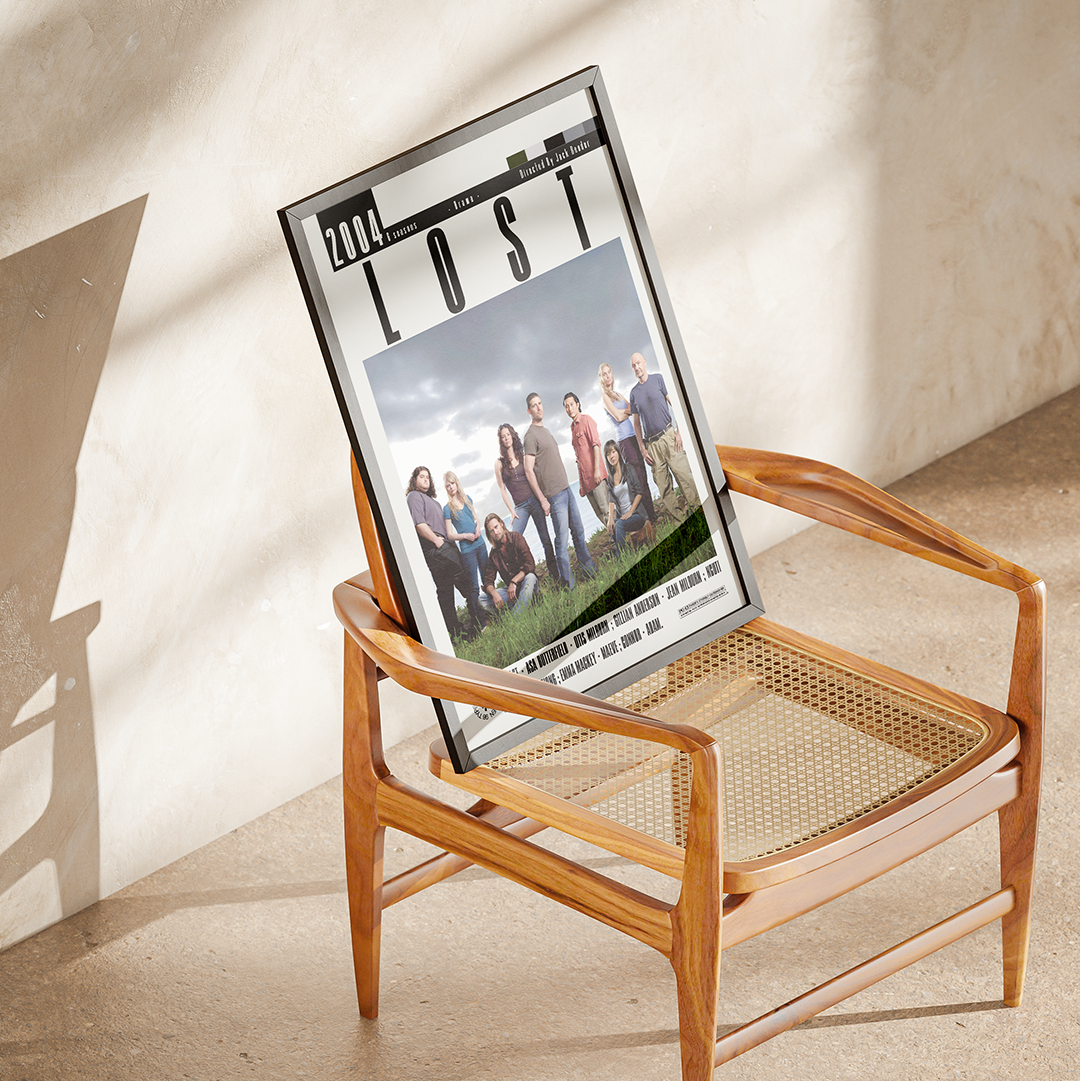 A framed poster of the TV show 'Lost' leaning against a wooden armchair in a sunlit room with a textured beige wall and floor.