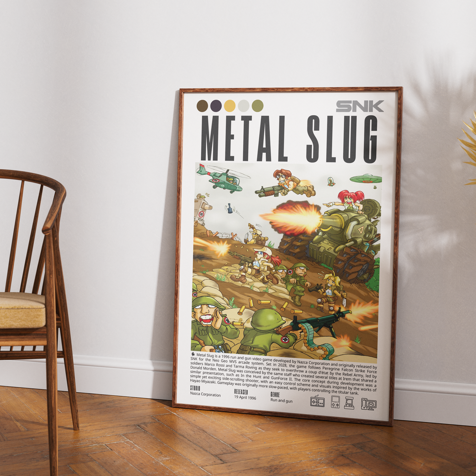 A framed Metal Slug comic-style poster leaning against a white wall on a wood floor, with part of a wooden chair visible on the left. The poster shows the SNK branding and illustrated soldiers, vehicles, and explosions.