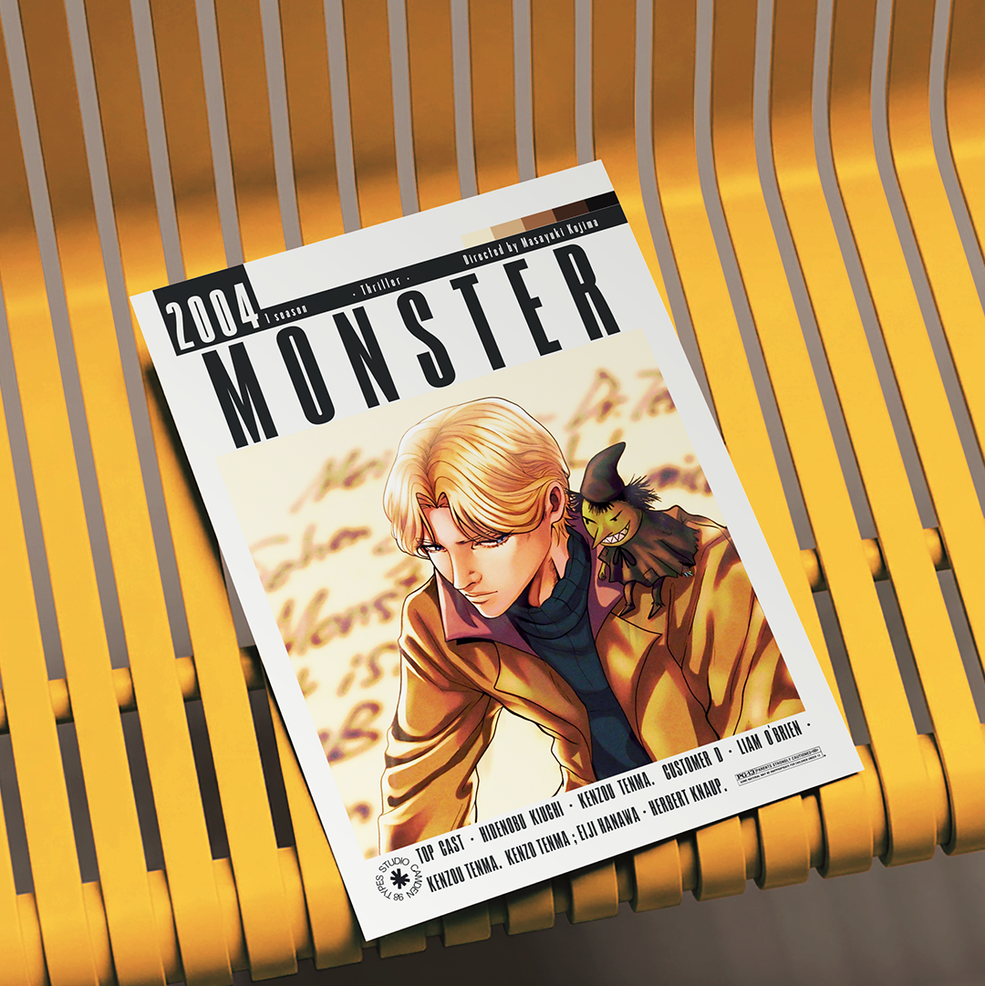 A printed magazine or comic cover titled "Monster" from 2004 lies on a yellow slatted chair. The cover features illustrated anime-style artwork of a blond man in a tan jacket with a small black cat on his shoulder.