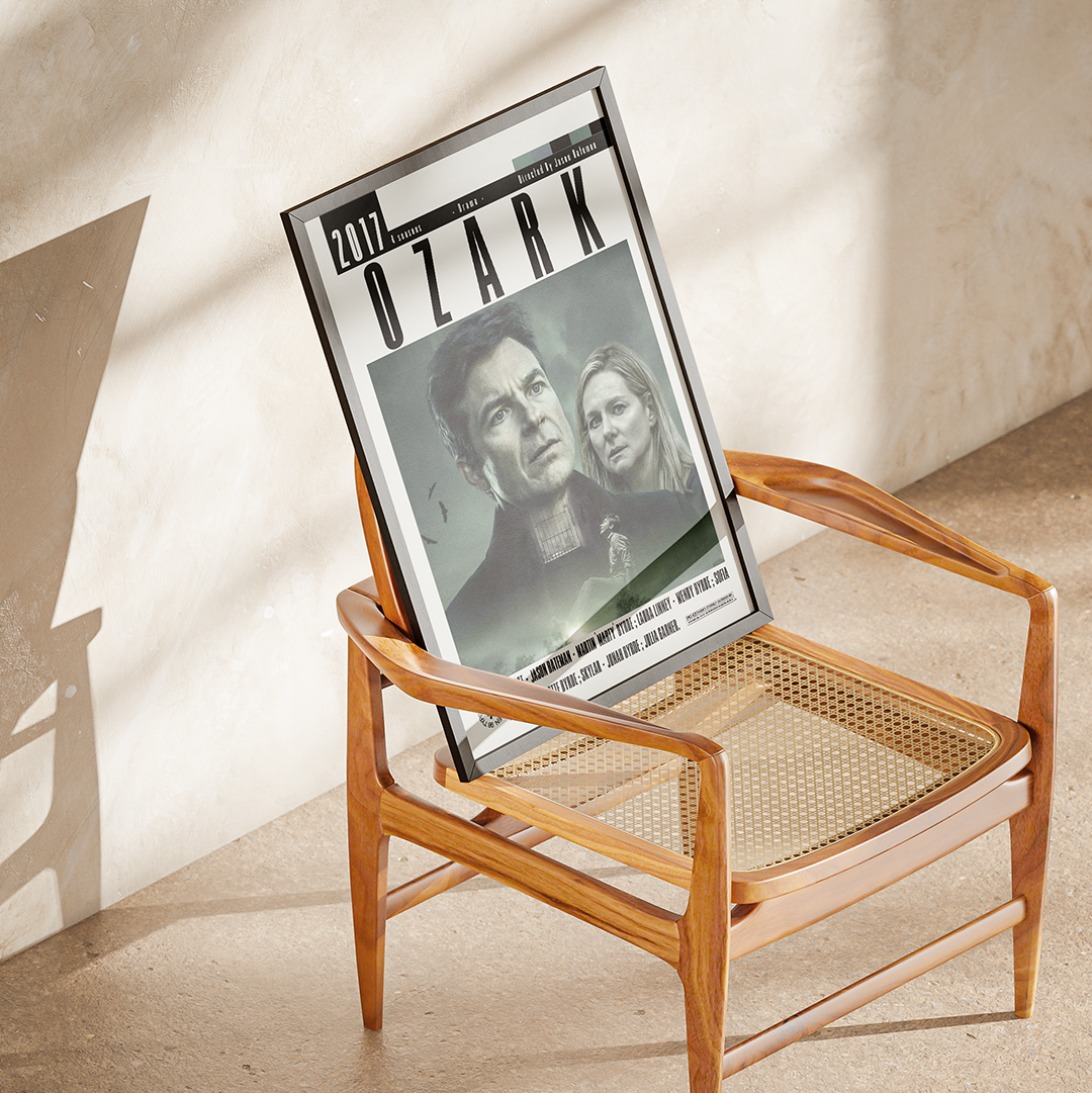 A framed Ozark movie poster leaning against a mid-century modern wooden armchair with a woven cane seat, set against a textured beige plaster wall with soft diagonal shadows.