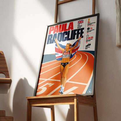 A framed poster of British athlete Paula Radcliffe leaning on a wooden table in a room with warm natural light and shadows.