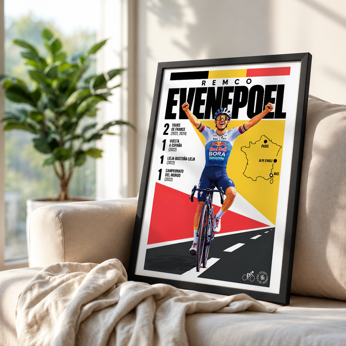A framed cycling poster featuring Remco Evenpoel leaning against a beige sofa in a bright living room, with a plant and window in the background.