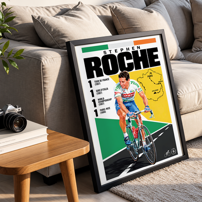 A framed cycling poster of Stephen Roche leaning against a beige sofa in a living room setting, with a small wooden side table and books in the foreground.