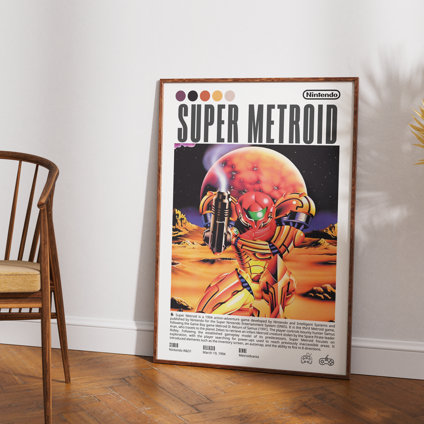 A framed retro-style Super Metroid poster leaning against a white wall on a wood floor, with part of a wooden chair visible on the left. The poster shows Samus in a gold and red suit against a desert-like scene with a large orange planet.