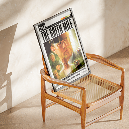 A framed 'The Green Mile' movie poster leaning against a wooden cane-seat chair in a sunlit room with a textured beige wall.
