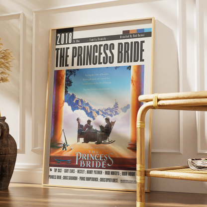 A framed 'The Princess Bride' movie poster leaning against a white paneled wall on a wooden floor, with a bamboo side table and decorative vase nearby.