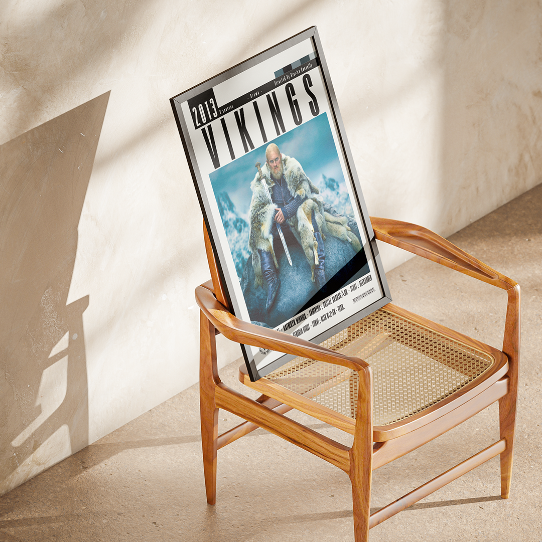 A framed art print featuring a Viking warrior on ice, styled on a mid-century modern wooden armchair with a cane seat against a textured beige plaster wall.