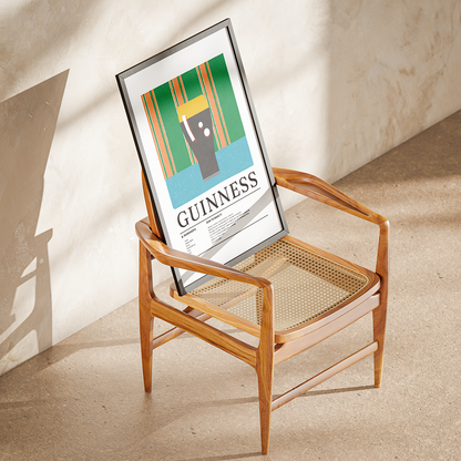 A framed Guinness poster leaning against a wooden armchair in a sunlit room with a textured beige wall and floor.