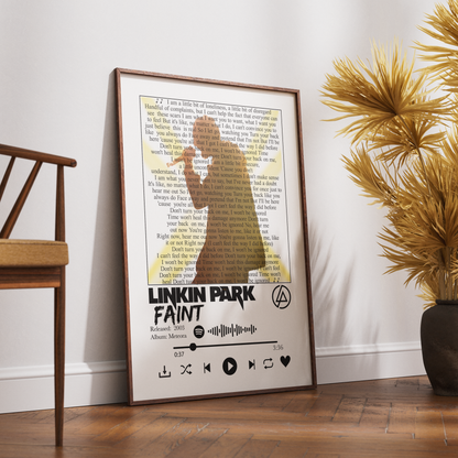 A framed Linkin Park 'Faint' poster leaning against a white wall on a wooden floor, styled in a room with a wooden chair and a potted palm.