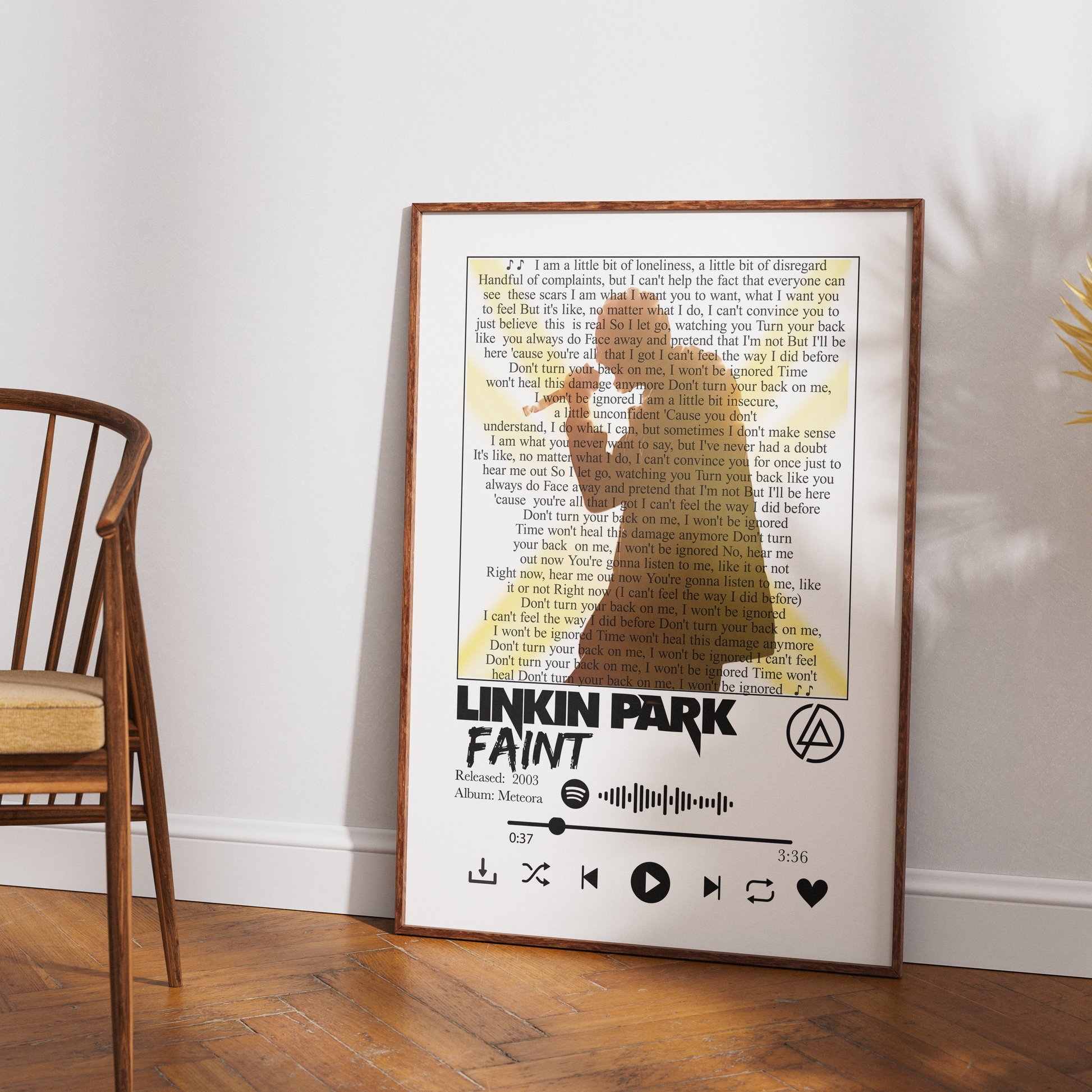 A framed Linkin Park 'Faint' album art print leaning against a white wall on a wooden floor, with a wooden chair partially visible on the left.